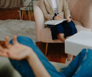 therapist sitting with legs crossed taking notes during a therapy session